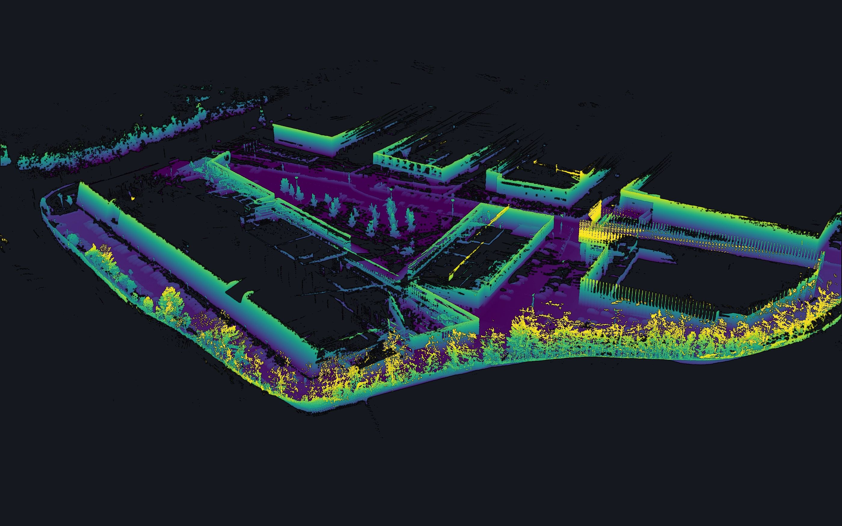 El mismo recinto en nube de puntos LiDAR real, visto desde el norte: el perímetro con su arbolado y los edificios, coloreados por altura.